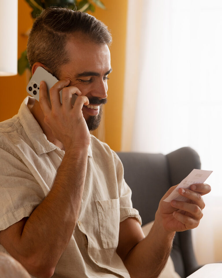 Mann bespricht einen Umzug telefonisch neben Umzugskartons